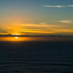 Sun behind clouds line at the ocean