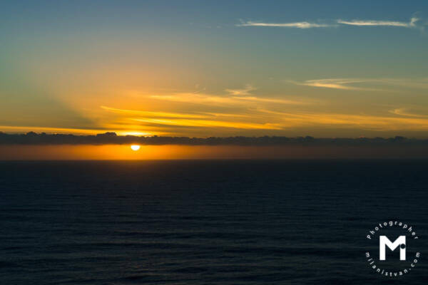 Sun behind clouds line at the ocean