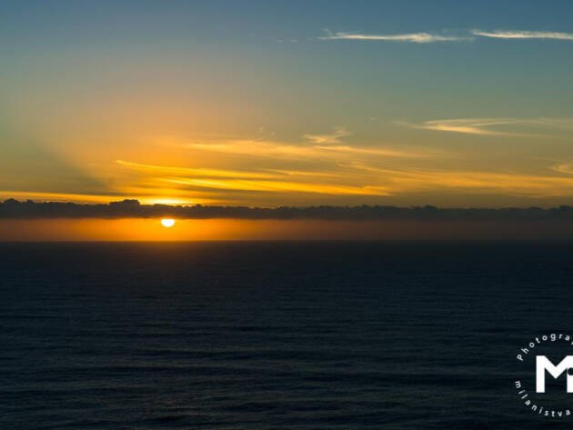 Sun behind clouds line at the ocean