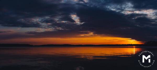 Sunset behind the clouds at the lake