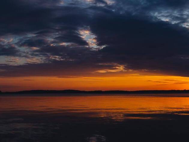 Sunset behind the clouds at the lake