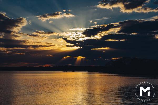 Big ray of sunshine behind the clouds at the lake