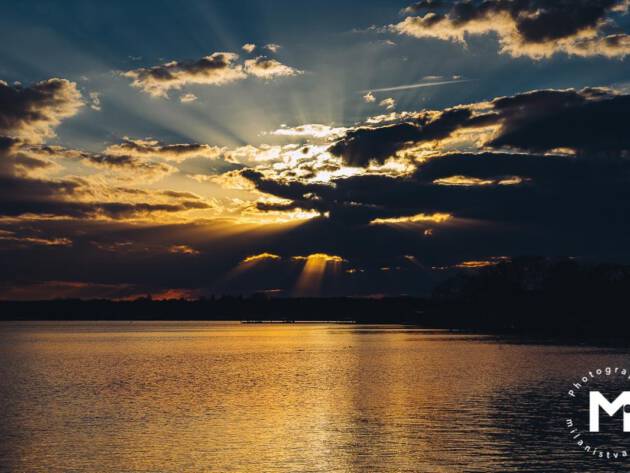 Big ray of sunshine behind the clouds at the lake